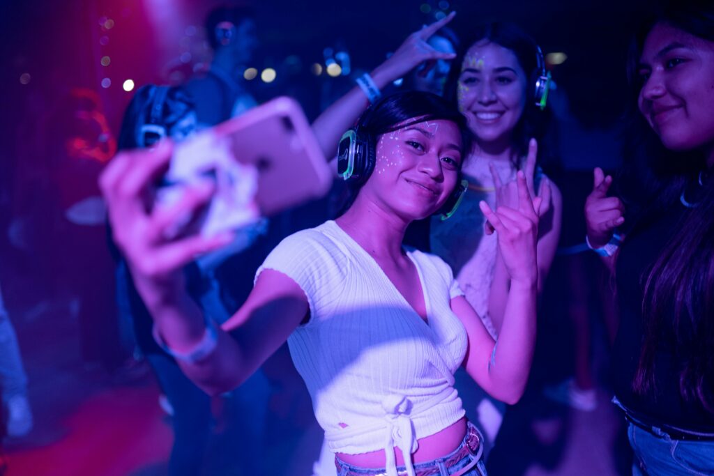 pexels-photo-2240763-2240763 Young adults enjoying a silent disco party, capturing selfies amidst colorful lights.