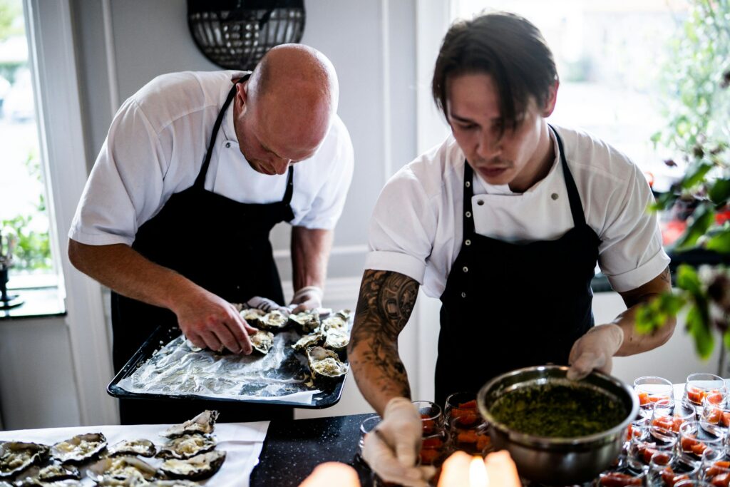 pexels-photo-3217156-3217156 Two chefs in a restaurant kitchen preparing gourmet dishes with fresh ingredients and focused expressions.