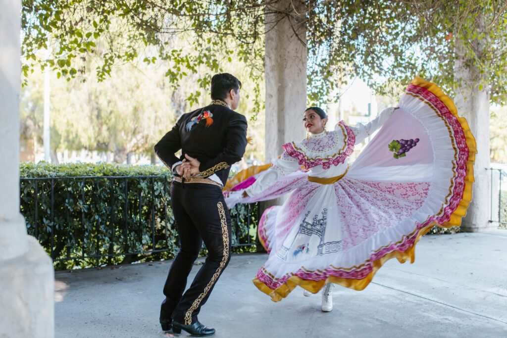 pexels-photo-8639346-8639346 A couple performs traditional Mexican folk dance outdoors in vibrant costumes.